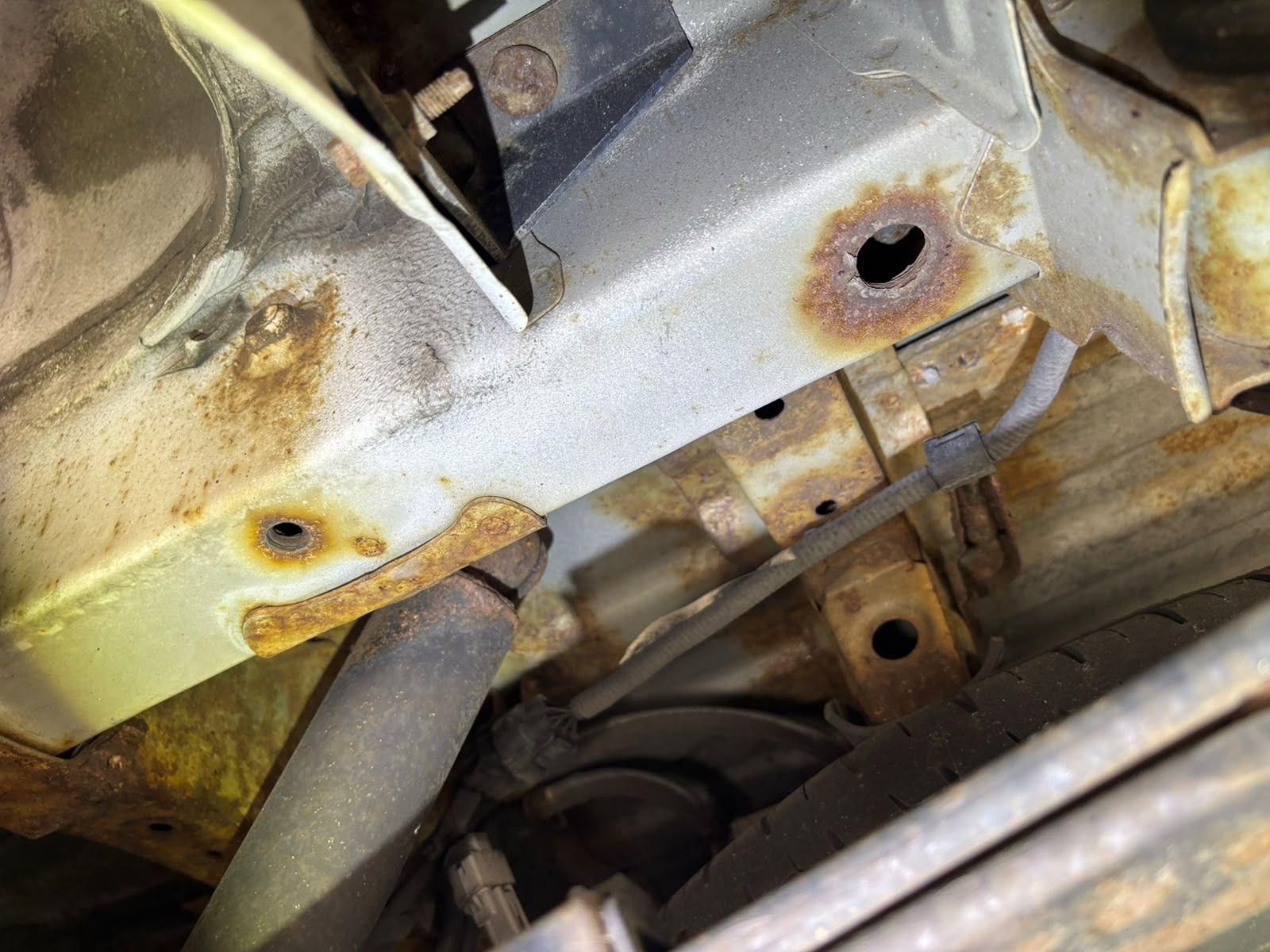 Inspector photo — crossmember rust holes