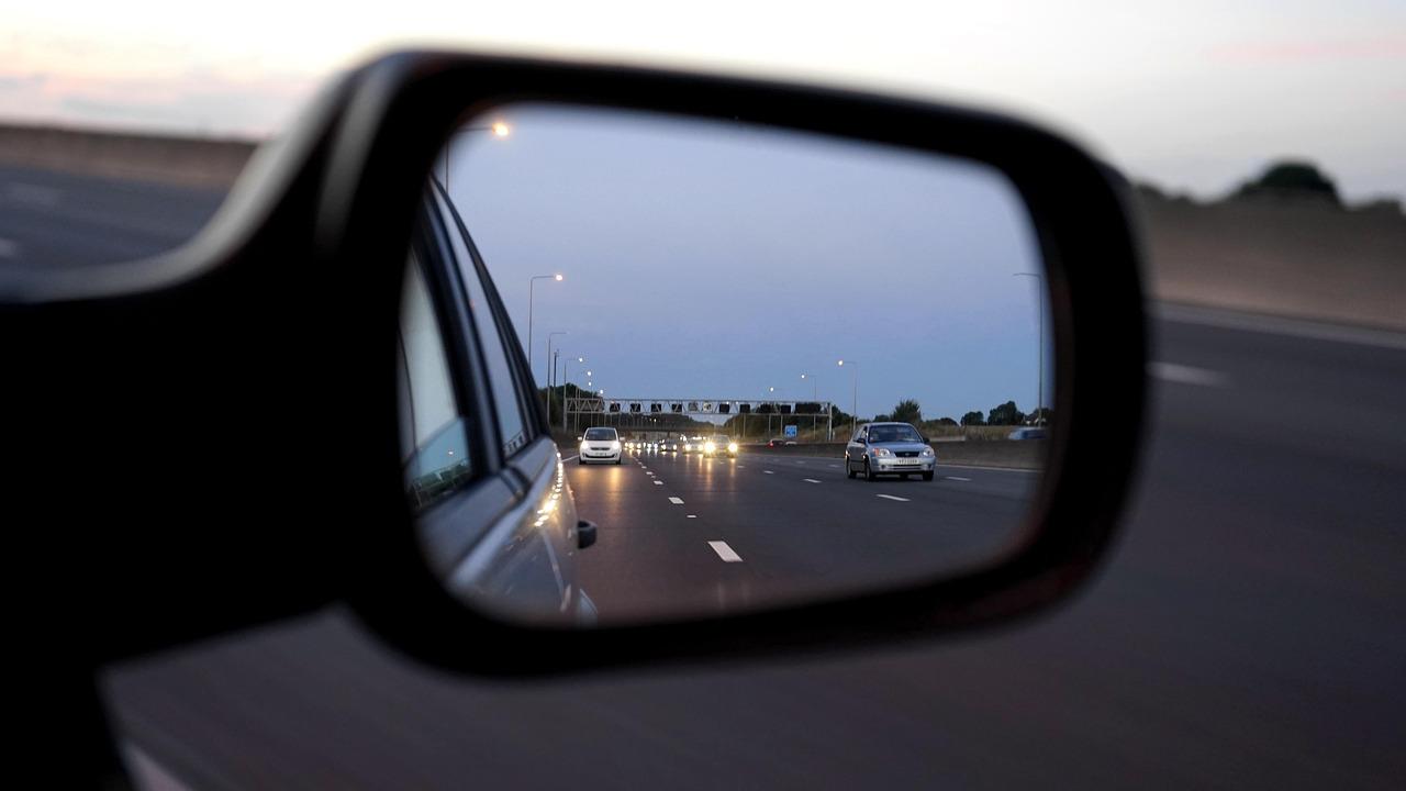 Side mirror reflecting cars on a multi-lane motorway at dusk Side mirror reflecting cars on a multi-lane motorway at dusk